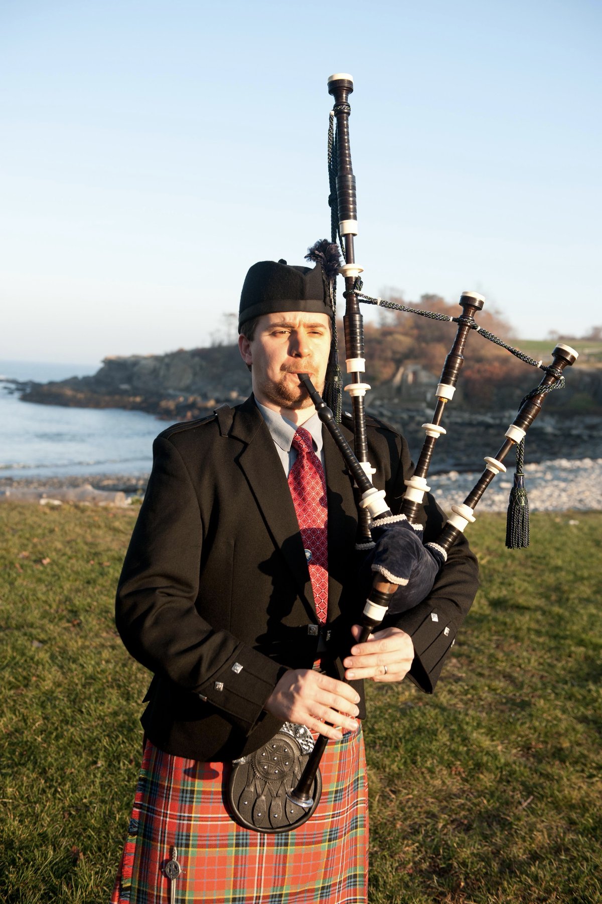 Dr. John Daggett playing bagpipes on the Maine coast